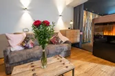Gemütliches Wohnzimmer mit Sofa, Kamin, Holztisch und Vase mit roten Rosen